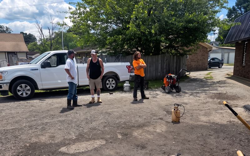 The crew standing on a graded gravel site with their truck