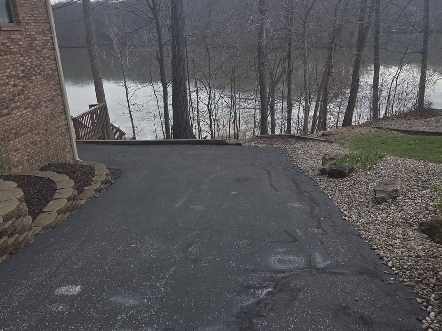 Old cracked asphalt driveway beside a lake, ready for tear-out