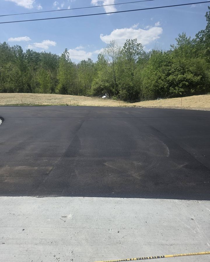Freshly paved commercial lot with a treeline behind it