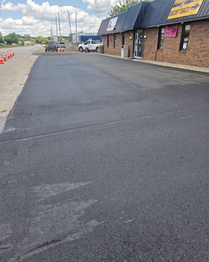 Freshly paved commercial parking lot in front of a strip of businesses